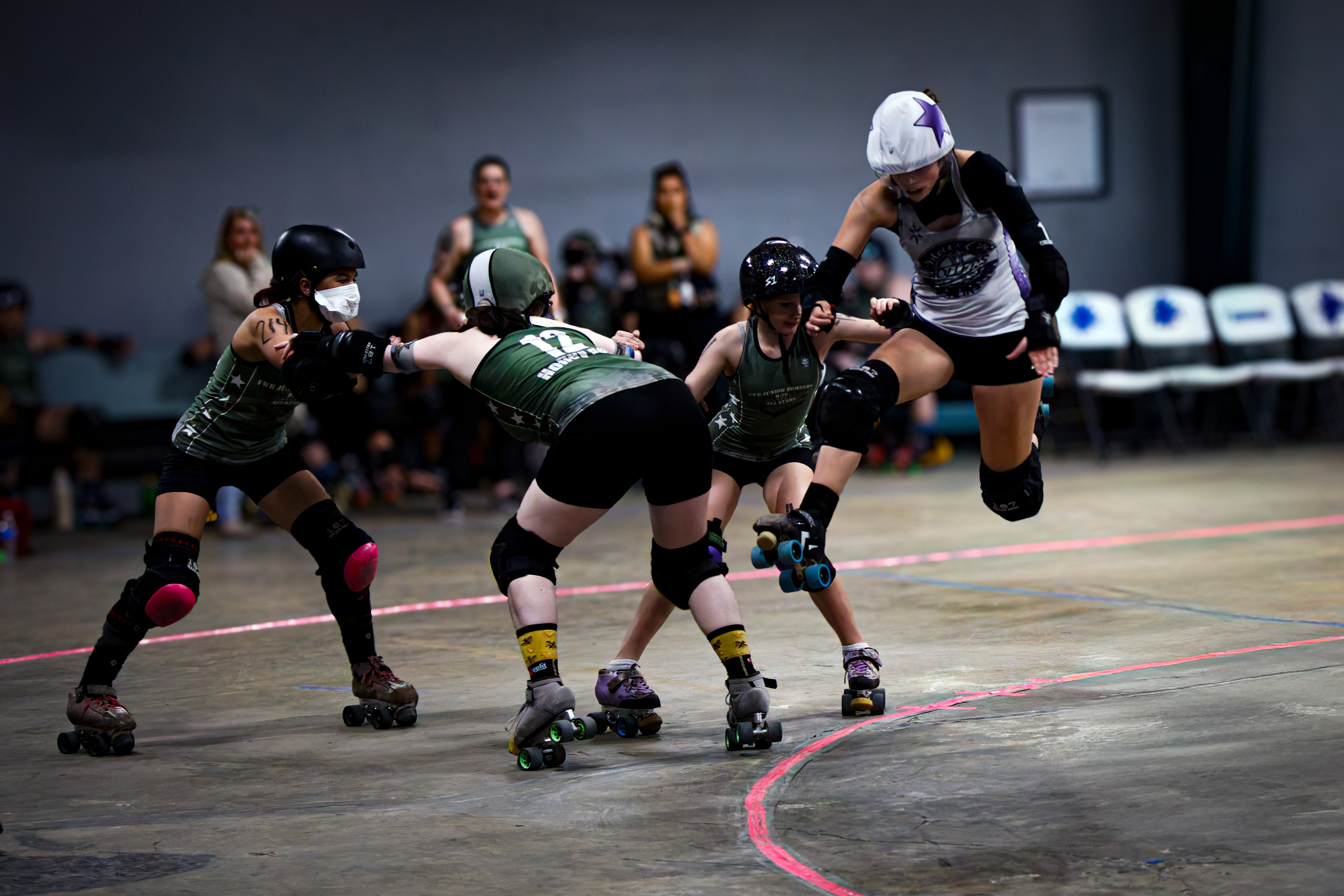 Nor'east Uprising junior roller derby jammer leaping past blockers during a jam